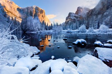Golden El Capitan above snow-covered stones of the Merced River