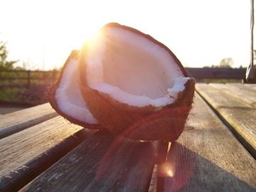 broken coconut on a coarse wooden table against the sun