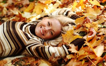 smiling girl lying in autumn maple leaves